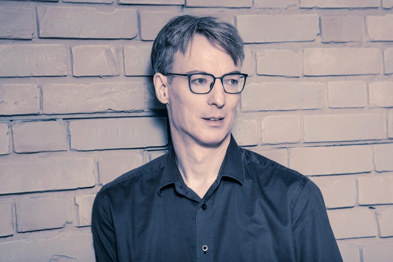 Ulrich Wegst, kurze graue Haare, schwarze Brille und schwarzes Hemd, lehnt an einer Backsteinwand. Ulrich Wegst, kurze graue Haare, schwarze Brille und schwarzes Hemd, lehnt an einer Backsteinwand.