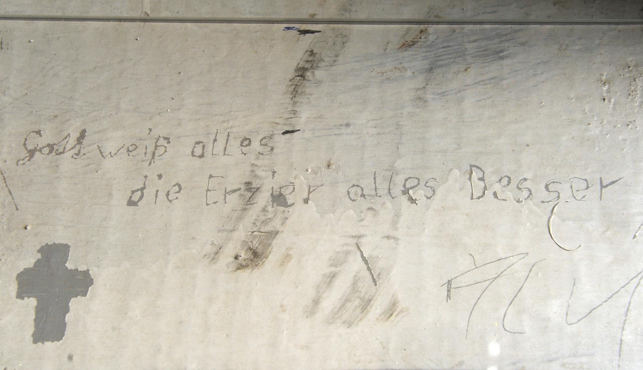Blick auf eine Originalinschrift auf einer Liege des ehemaligen Jugendwerkhofes in Torgau, wenige Tage vor dem Mauerfall. Darauf steht in falscher Rechtschreibung: "Gott weiß alles – die Erzieher alles besser"!