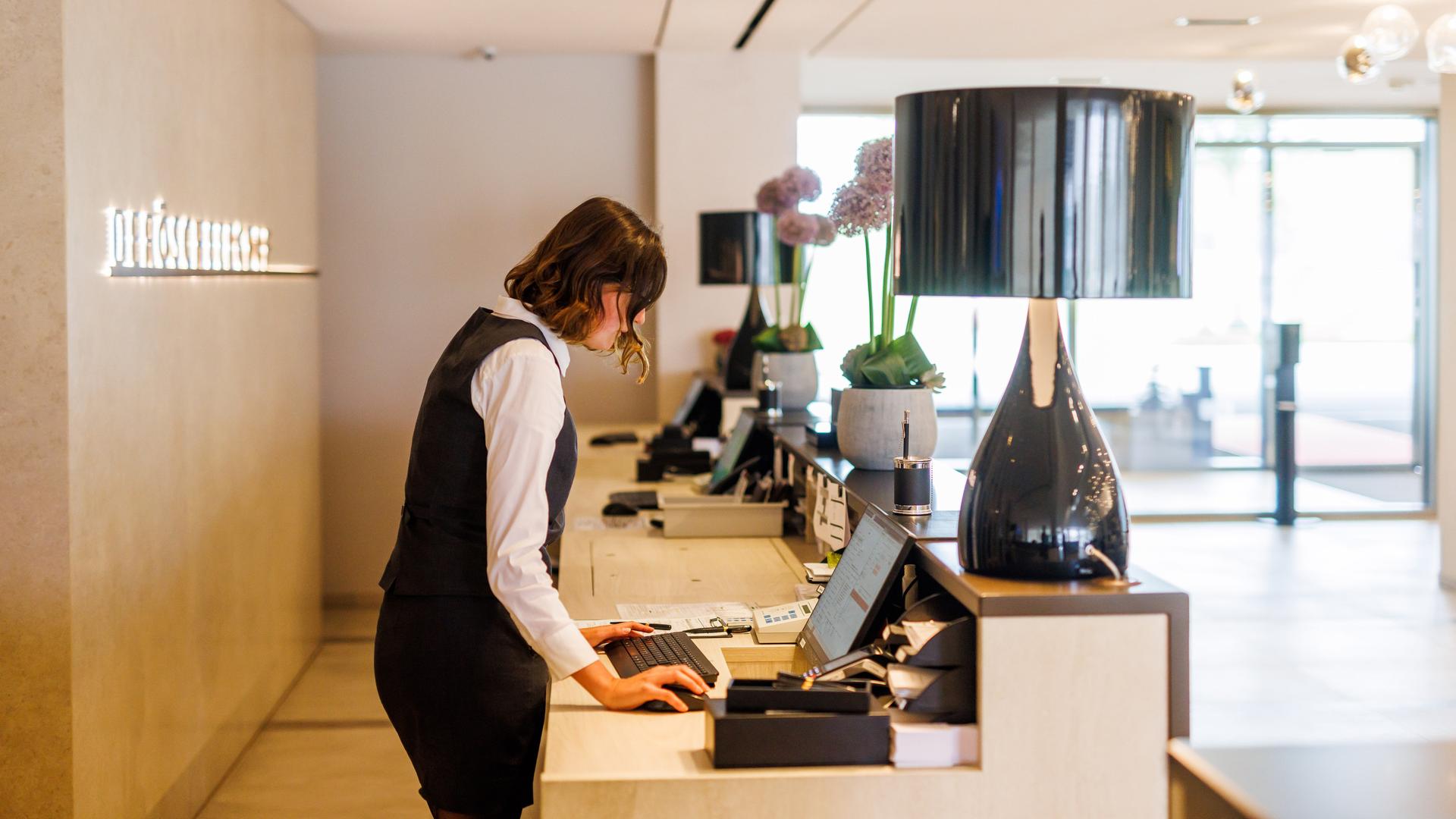 Eine Mitarbeiterin steht an der Rezeption eines Hotels. Eine Mitarbeiterin steht an der Rezeption eines Hotels.
