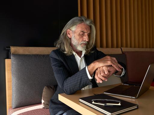 Geschäftsmann prüft in einem Café die Uhrzeit || Modellfreigabe vorhanden