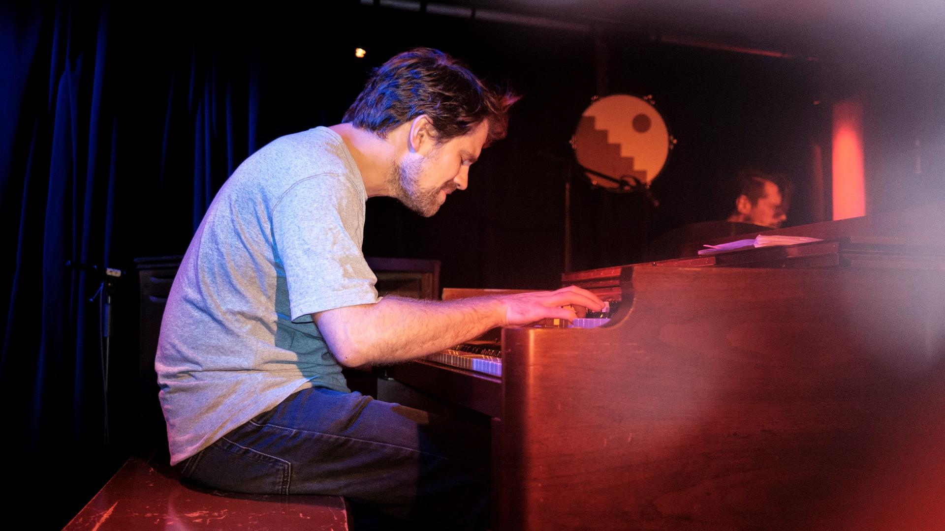 Kit Downes sitzt im grauen Shirt vertieft über einer Hammond-Orgel und spielt mit geschlossenen Augen auf einer Clubbühne. Kit Downes sitzt im grauen Shirt vertieft über einer Hammond-Orgel und spielt mit geschlossenen Augen auf einer Clubbühne.