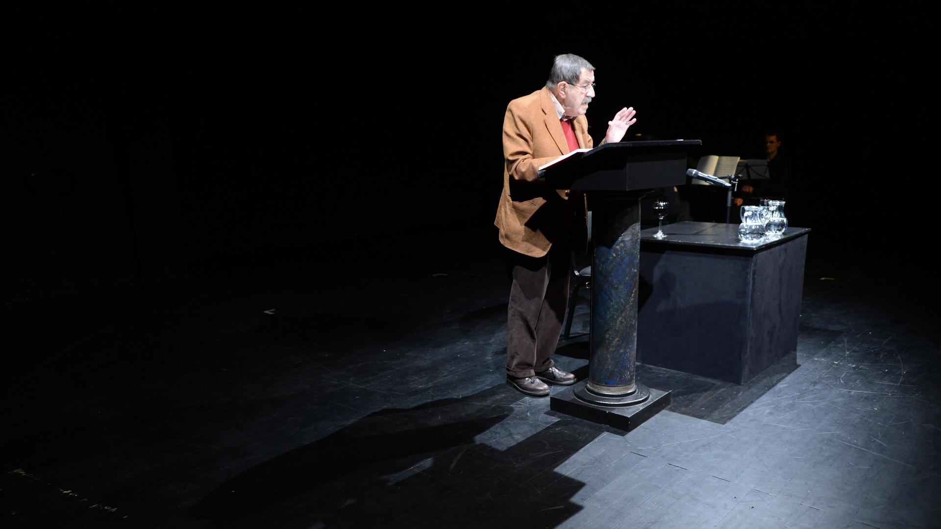 Der Schriftsteller Günter Grass steht auf einer Bühne vor einem Stehpult und liest aus einem Buch vor. Der Schriftsteller Günter Grass steht auf einer Bühne vor einem Stehpult und liest aus einem Buch vor.