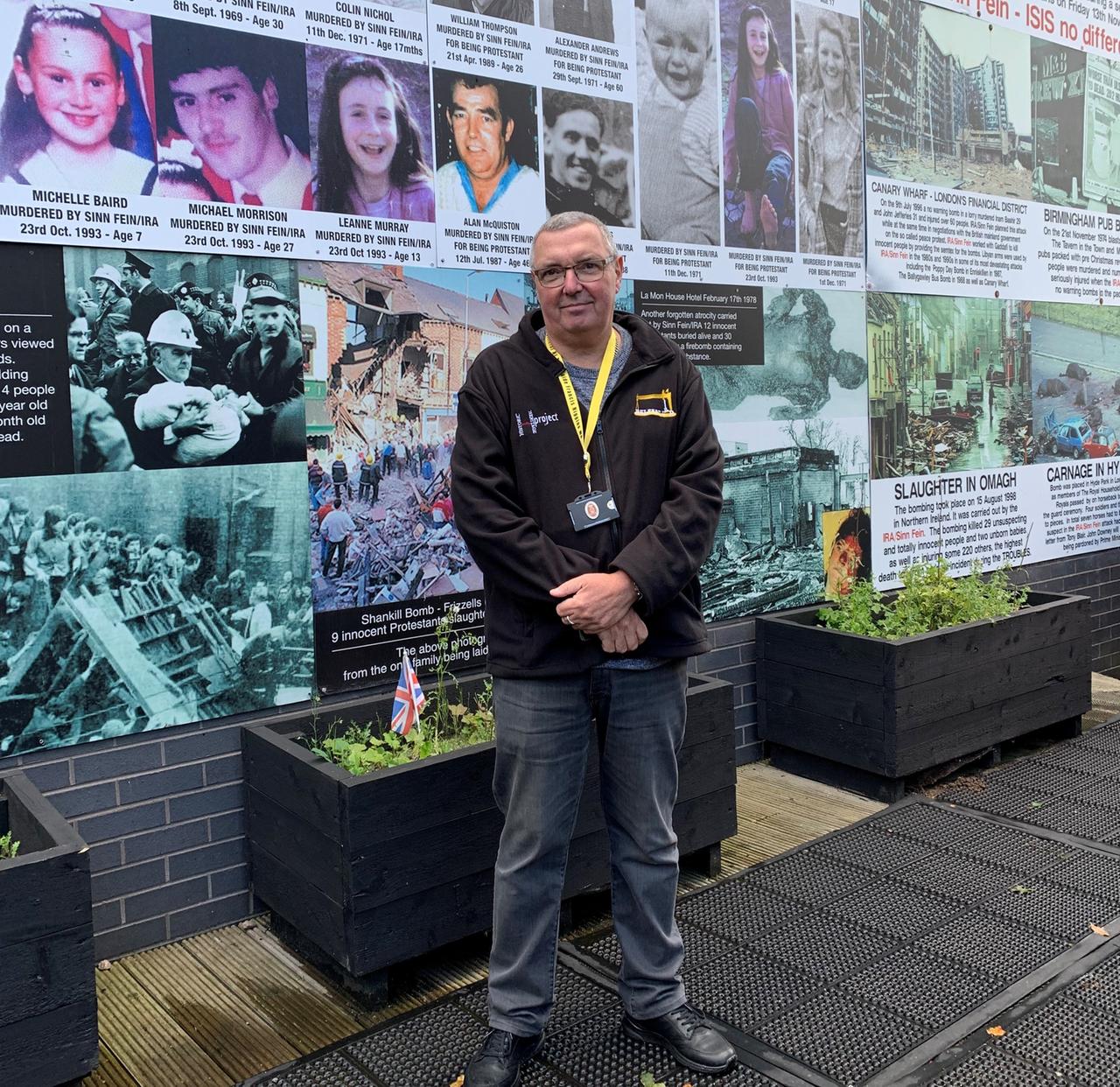 Frank steht vor einer Fotowand mit Opfern der IRA-Gewalt in Nordirland. Frank steht vor einer Fotowand mit Opfern der IRA-Gewalt in Nordirland.