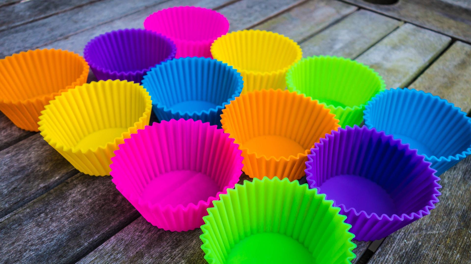 Farbige Silikon-Backformen für Muffins auf einem Holztisch. Silikon Backforrmencolored Silicone Back forms for Muffins on a Wooden table Silicone Farbige Silikon-Backformen für Muffins auf einem Holztisch. Silikon Backforrmencolored Silicone Back forms for Muffins on a Wooden table Silicone