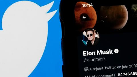 Elon Musks Twitter Profil auf einem Smartphone, daneben das Logo von Twitter