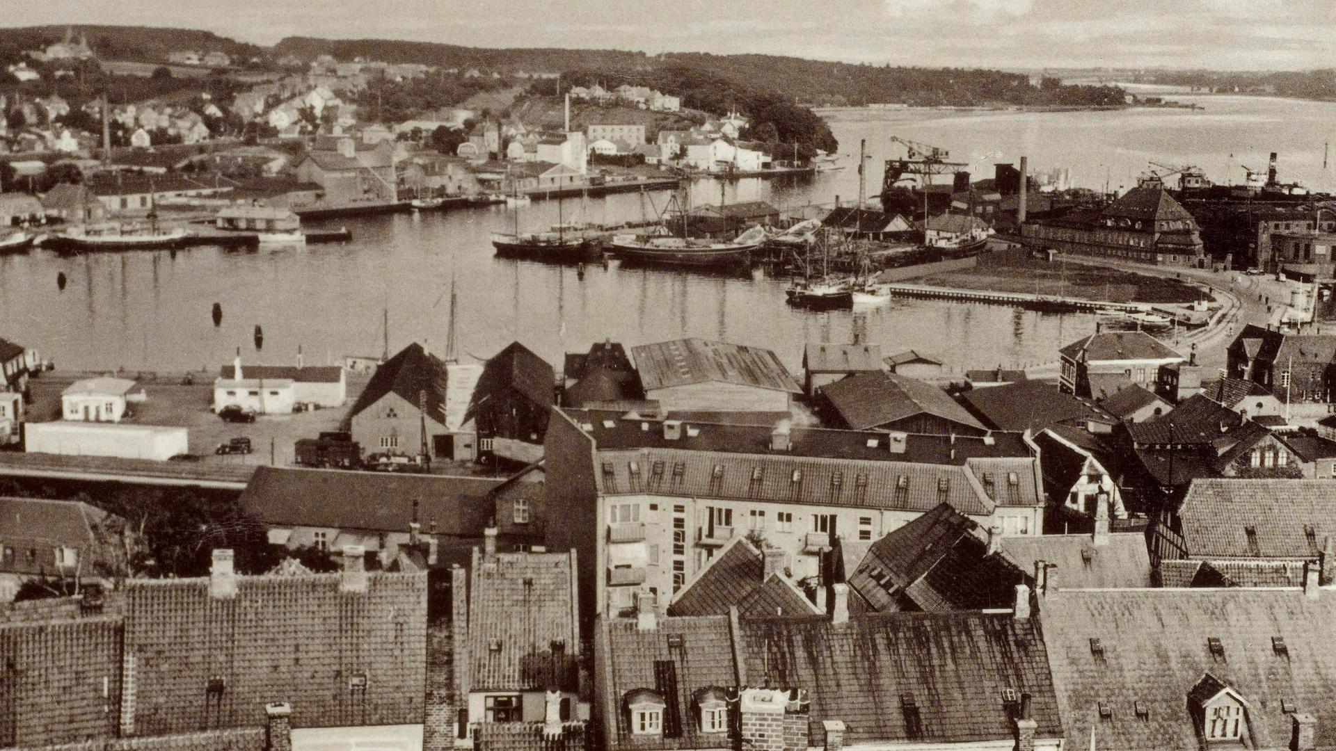 Ein Schwarz-Weiß-Foto aus den 1930er-Jahren zeigt eine Ansicht von Svendborg mit dem Hafen. Ein Schwarz-Weiß-Foto aus den 1930er-Jahren zeigt eine Ansicht von Svendborg mit dem Hafen.
