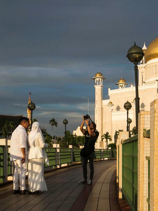 Ein frisch verheiratetes Paar lässt sich vor der Moschee Sultan Omar Ali Saifuddien in Brunei fotografieren, 2019.