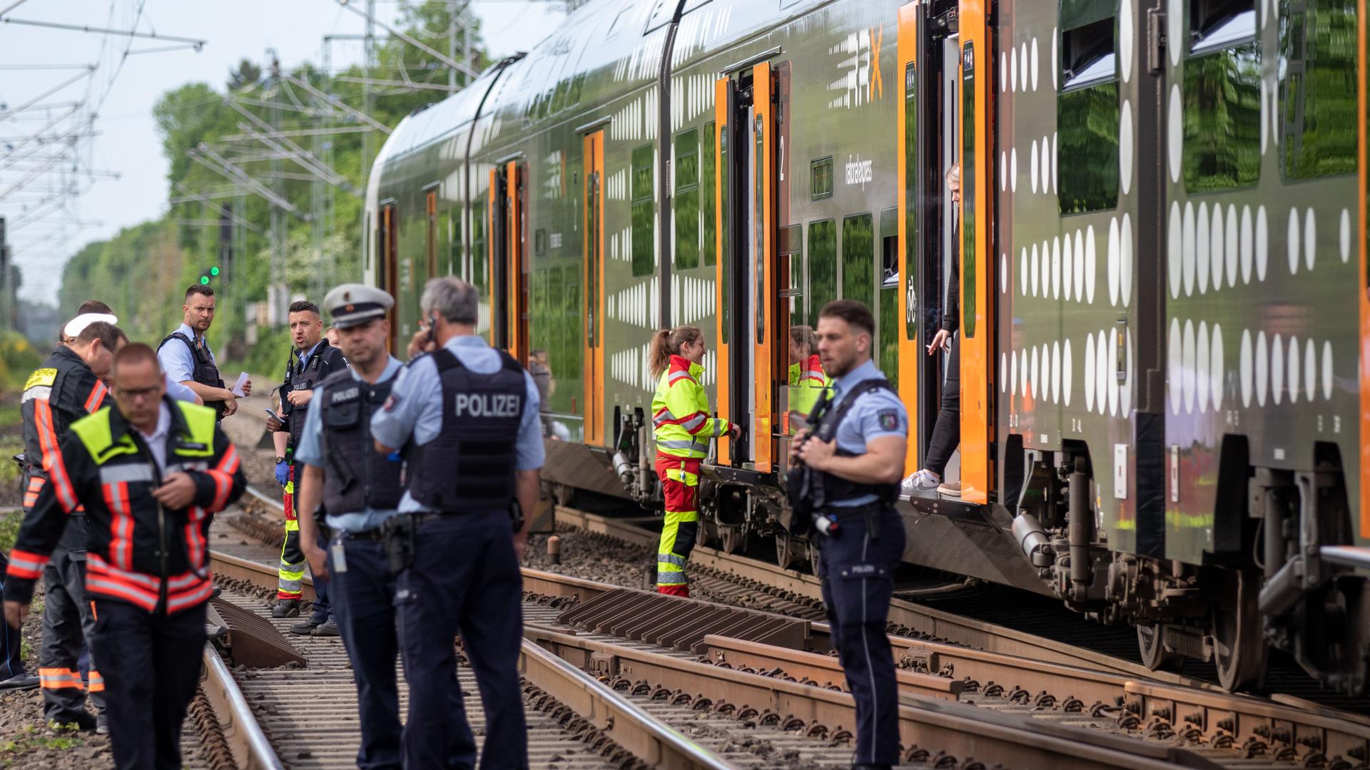 Ein stehender Zug, Polizisten stehen auf den Gleisen.