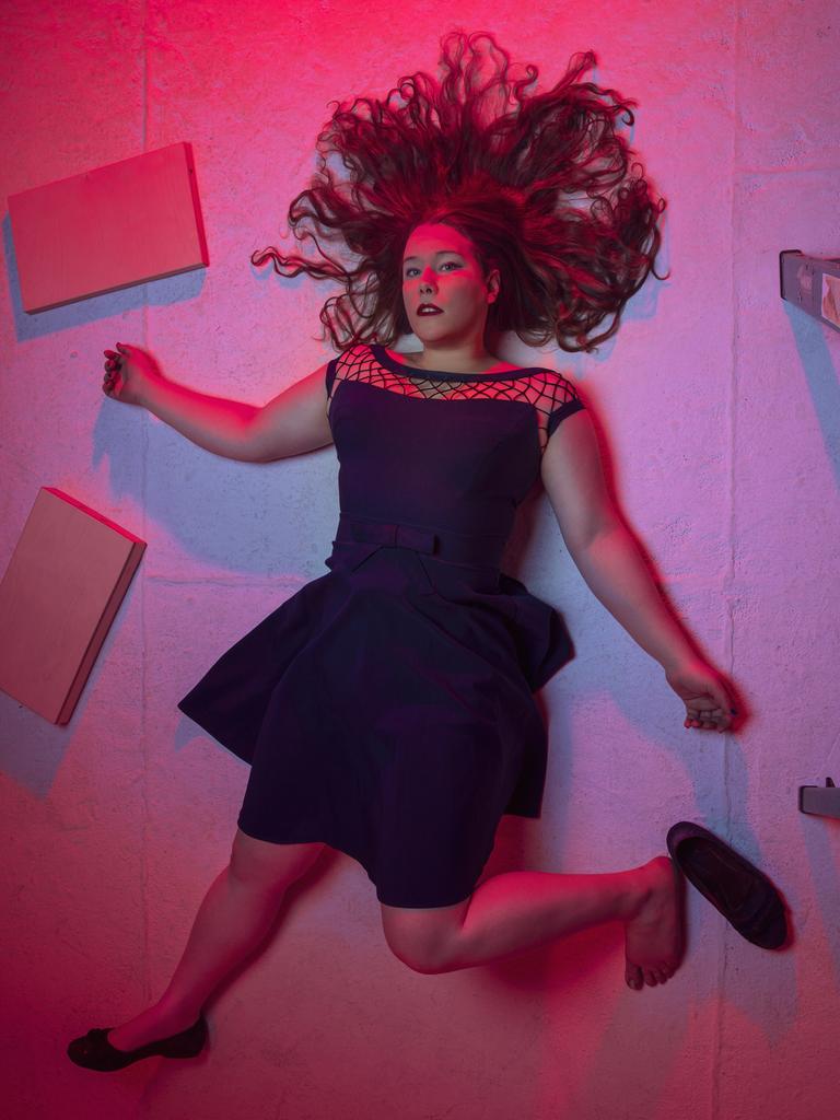 Porträt von Lucia Lucas, die in rötlichem Licht mit ausgebreiteten Haaren und aufgestelltem Fuß auf dem Boden liegt