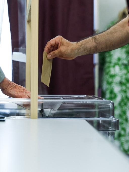 Wahlzettel und -urne beim ersten Wahlgang der Parlamentswahl 2022 in Frankreich