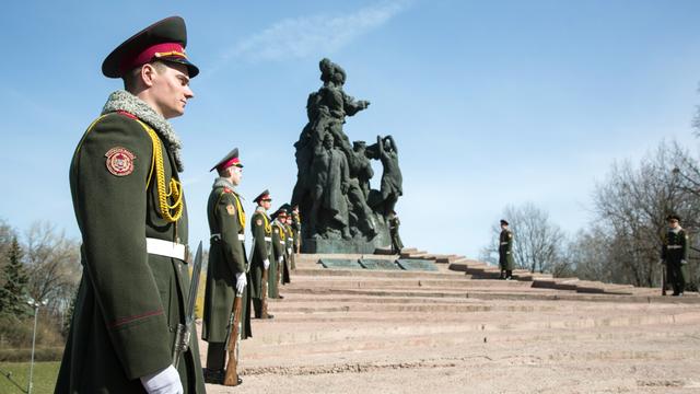 Ukrainische Soldaten stehen vor einer Statue der Gedenkstätte in Babi Jar.