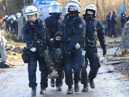 Polizisten tragen einen Klimaaktivisten vom besetzten Braunkohleort Lützerath weg.