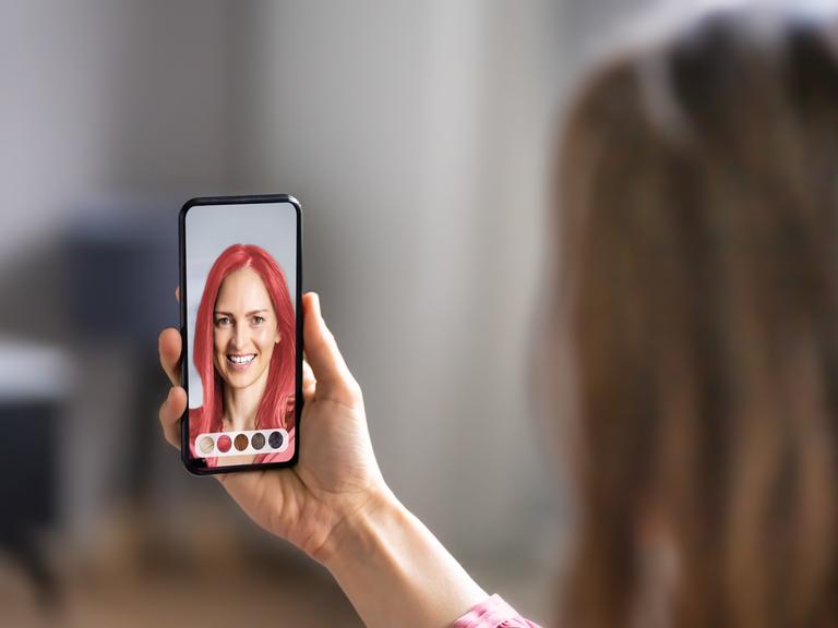 Eine junge Frau macht ein Selfie von sich und verändert das Bild mit einem Foto-Filter.
