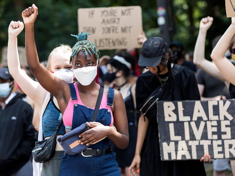 Zwei junge Frauen heben ihre Hände auf der Black Lives Matter Demonstration gegen Rassismus auf der Strasse des 17. Juni. Berlin, 27.06.2020.