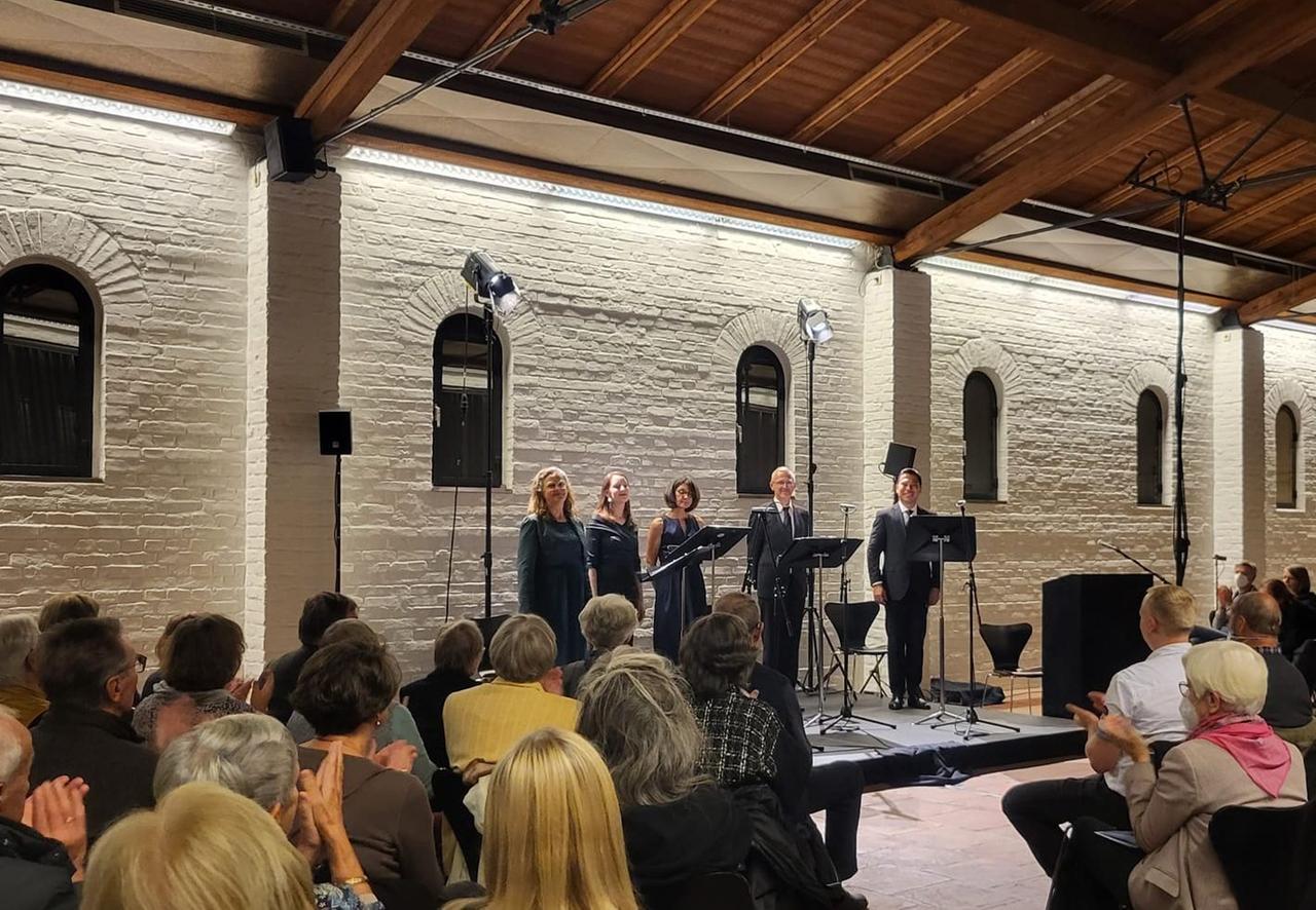 Die Konzertsängerinnen und -sänger sowie die Sprecherin nehmen den Beifall der Zuschauer in der Hall mit großem Holzdach lachend entgegen. Die Konzertsängerinnen und -sänger sowie die Sprecherin nehmen den Beifall der Zuschauer in der Hall mit großem Holzdach lachend entgegen.
