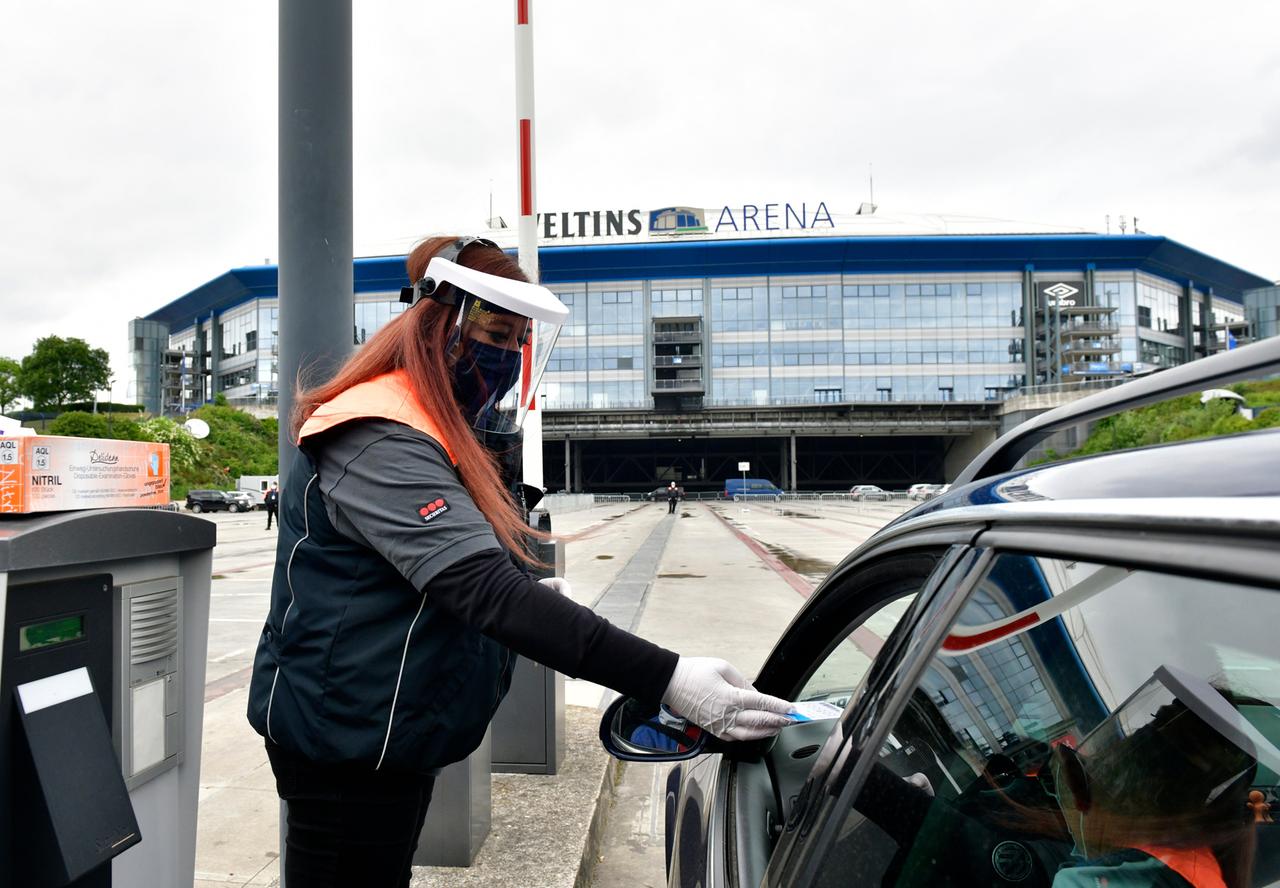 Ein Steward kontrolliert mit Gesichtsschutz und mit medizinischem Mundschutz vor der Veltins-Arena vor dem Spiel Tickets. Ein Steward kontrolliert mit Gesichtsschutz und mit medizinischem Mundschutz vor der Veltins-Arena vor dem Spiel Tickets.