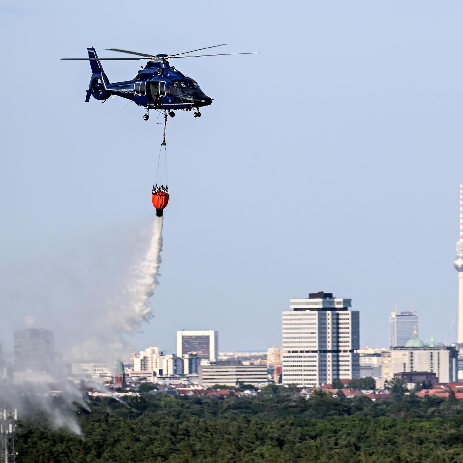 Berlin: Ein Hubschrauber der Bundespolizei wirft Wasser über der Brandstelle im Grunewald ab.