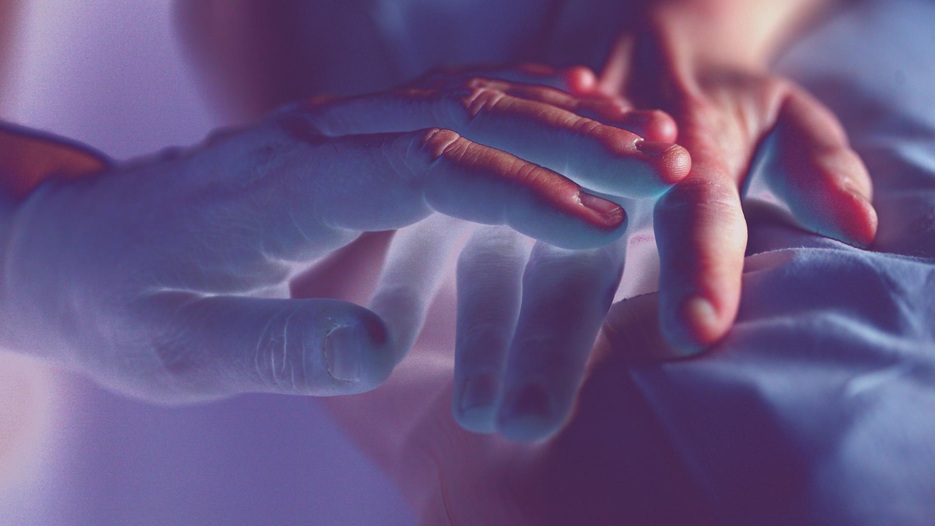farblich verfremdete Großaufnahme einer Hand, die eine andere Hand tröstend streichelt farblich verfremdete Großaufnahme einer Hand, die eine andere Hand tröstend streichelt