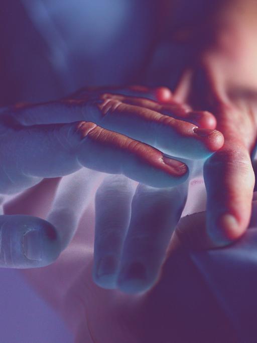 farblich verfremdete Großaufnahme einer Hand, die eine andere Hand tröstend streichelt