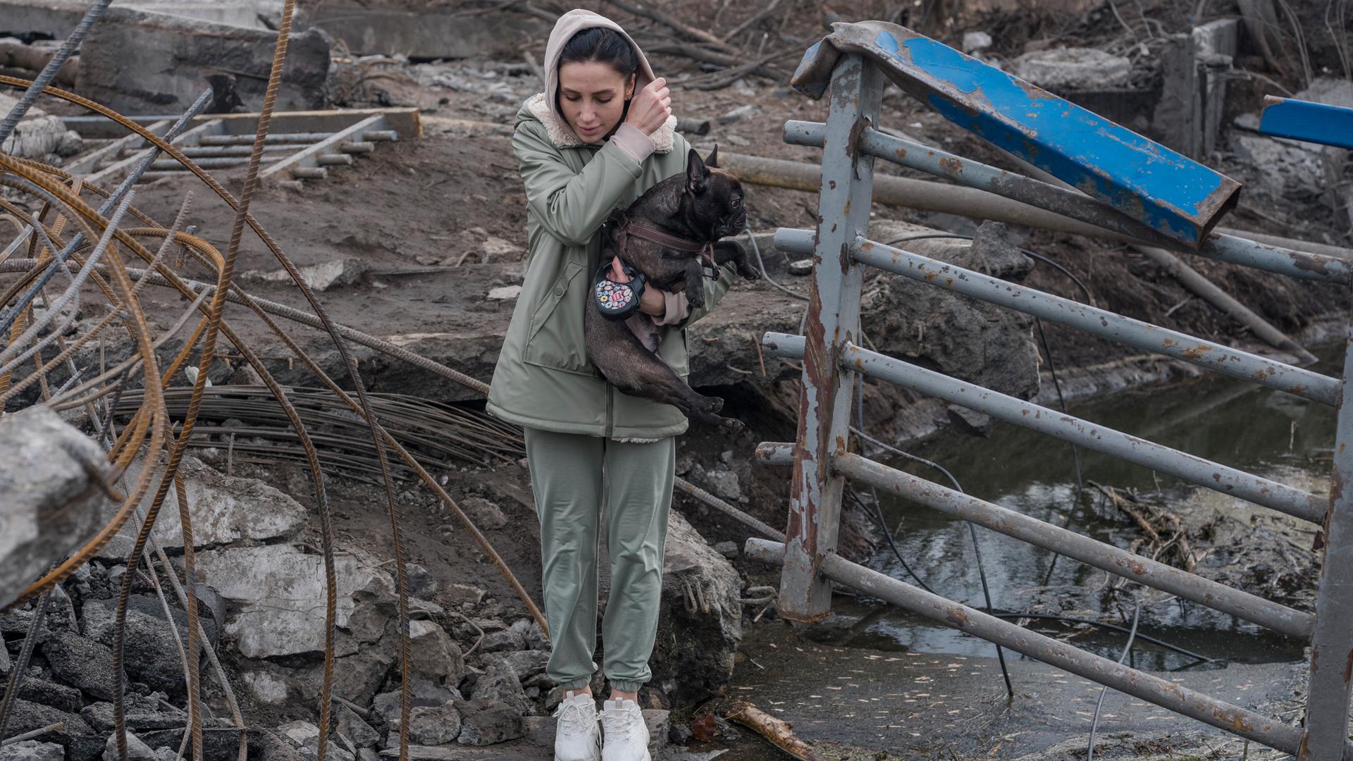 Eine junge Frau versucht mit einem Hund in den Armen einen Fluss zu überqueren. Eine junge Frau versucht mit einem Hund in den Armen einen Fluss zu überqueren.