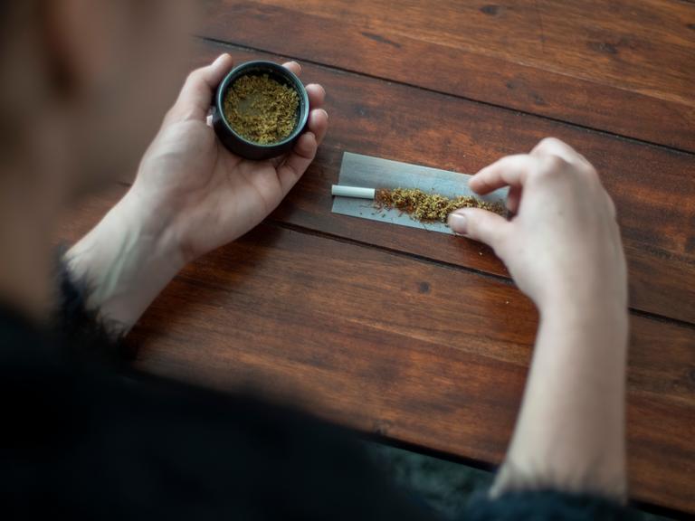 Eine Frau baut mit Marihuana einen Joint (Tüte). Zu sehen sind eine kleine Dose mit Marihuana und auf dem Tisch ein noch nicht gedrehter Joint. Copyright: Julia Imo/ picture alliance/photothek