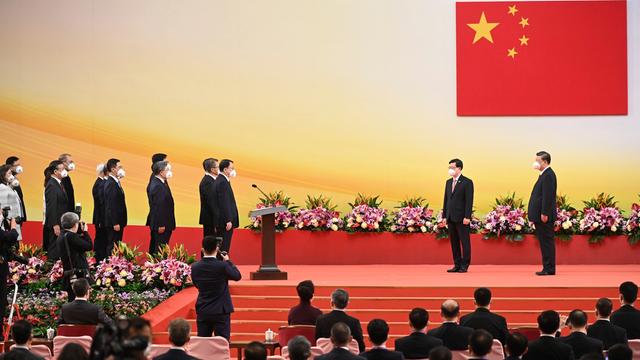 Xi Jinping (r), Chinas Präsident, steht neben Hongkongs neuem Regierungschef John Lee, während Mitglieder von Lees Regierung vereidigt werden. Im Hintergrund die chinesische Fahne.