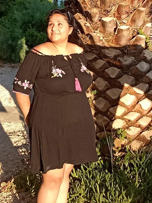 Eine Frau in einem Kleid steht vor einer Palme: Adoptionsberaterin Melanie Kleintz