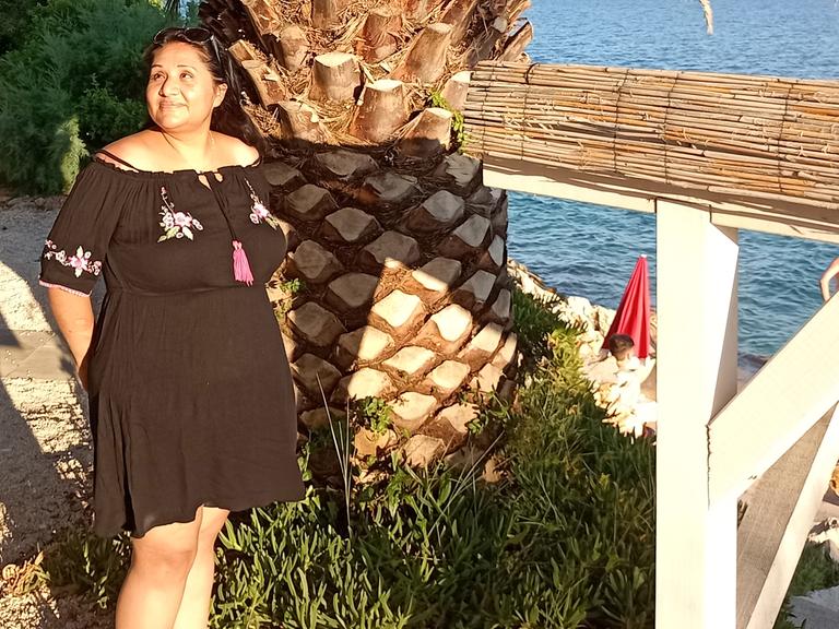 Eine Frau in einem Kleid steht vor einer Palme: Adoptionsberaterin Melanie Kleintz