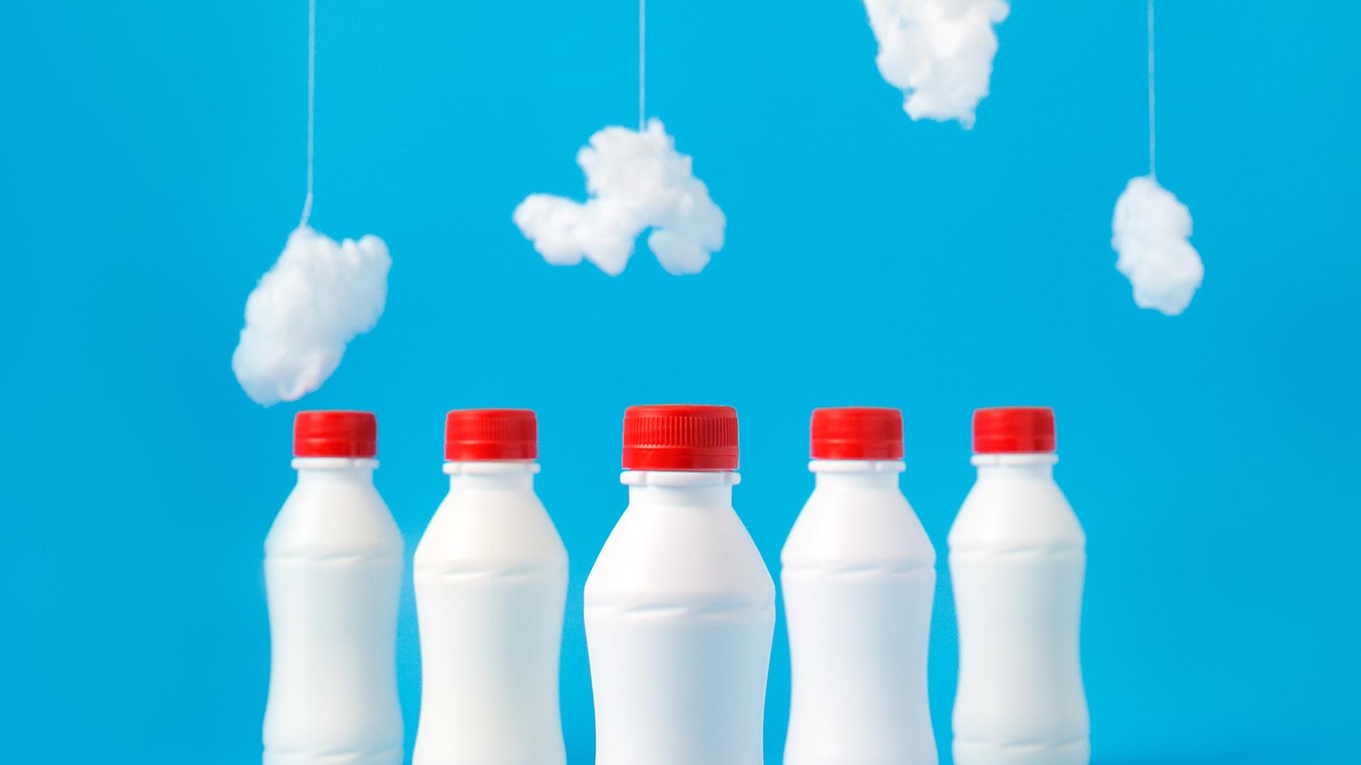 Fünf weiße Plastikflaschen mit rotem Deckel vor blauem Hintergrund. Im oberen Bildbereich hängen kleine Wolken aus Watte. Fünf weiße Plastikflaschen mit rotem Deckel vor blauem Hintergrund. Im oberen Bildbereich hängen kleine Wolken aus Watte.