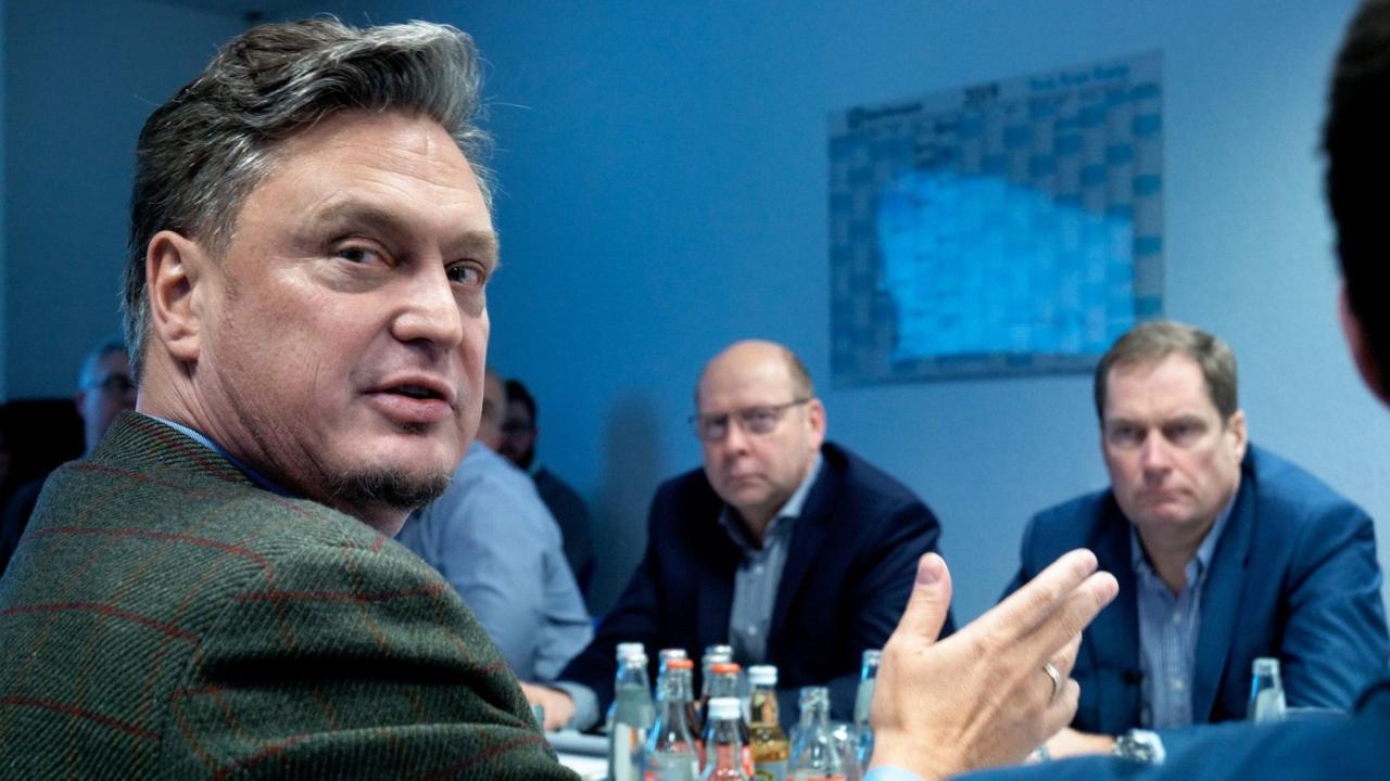 Filmstill aus "Eine deutsche Partei", mehrere AfD-Mitglieder sitzen mit Frank Hansel  (Parlamentarischer Geschäftsführer der AfD Fraktion im Berliner Abgeordnetenhaus) um einen Tisch und diskutieren miteinander. 