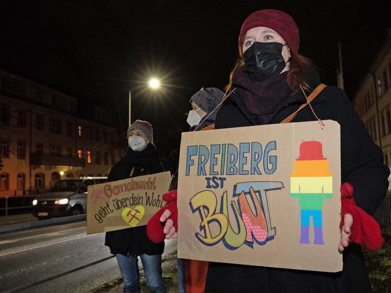 Eine Frau steht mit einem Schild in der Hand mit dem Text "Freiberg ist bunt"