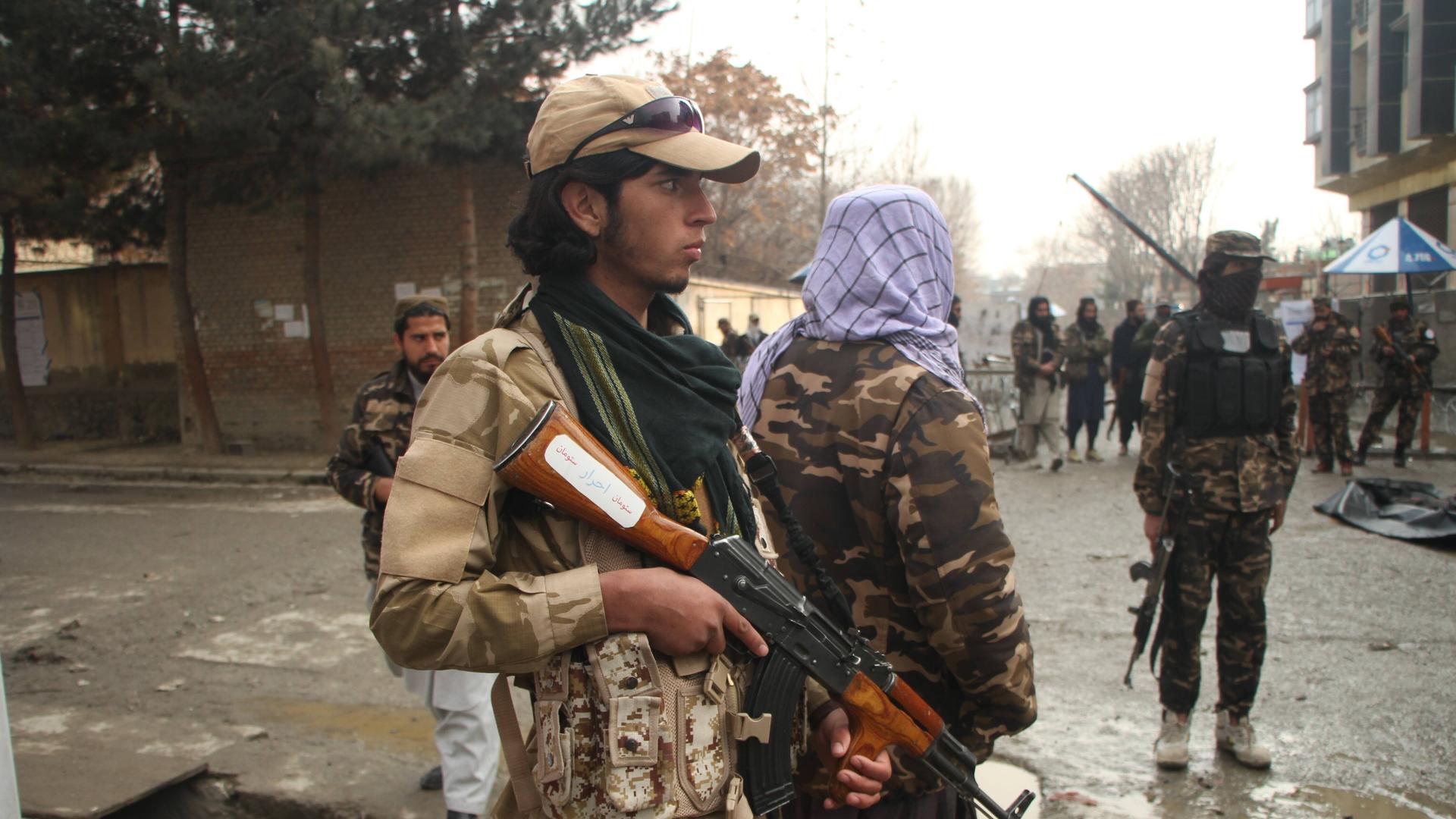 Taliban stehen mit Waffen auf einer Straße in Kabul.