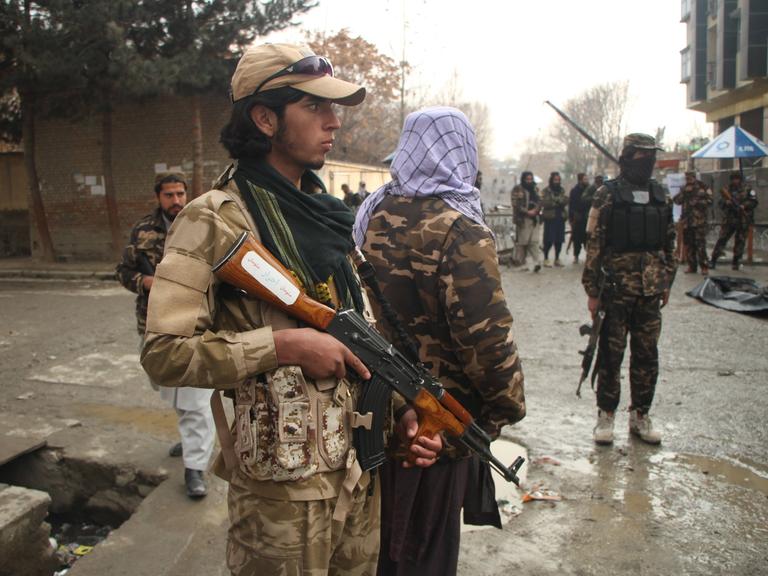 Taliban stehen mit Waffen auf einer Straße in Kabul.