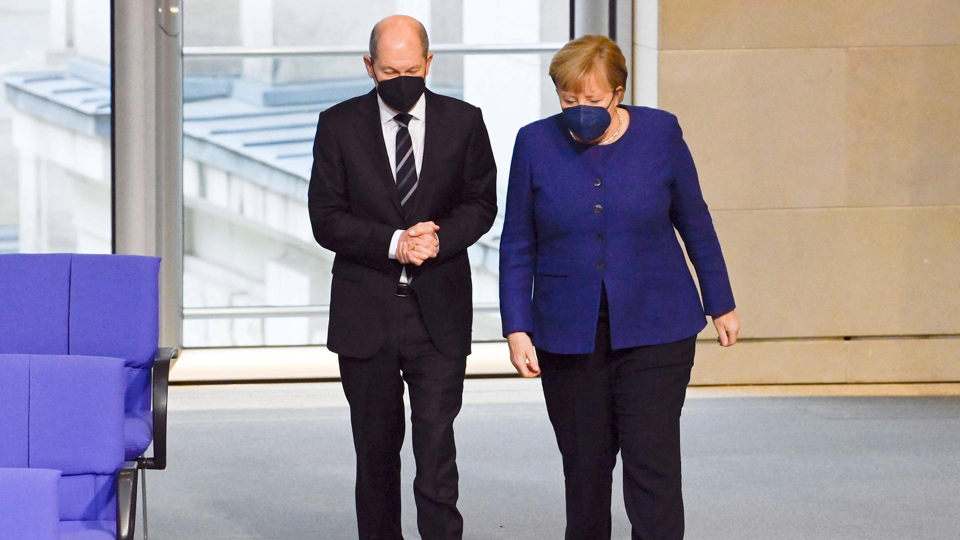 Olaf Scholz und Angela Merkel betreten nebeneinander das Plenum des Deutschen Bundestags.