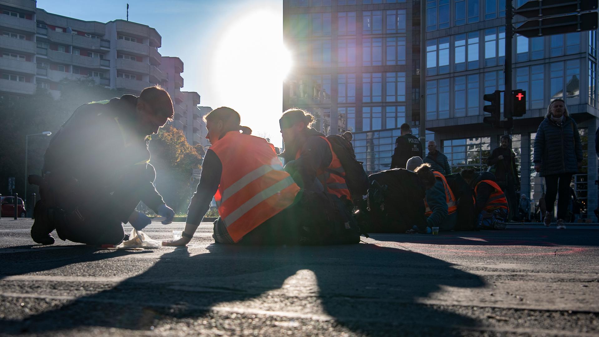 Ein Polizist versucht, die Hand eines Aktivisten von der Straße zu lösen. Ein Polizist versucht, die Hand eines Aktivisten von der Straße zu lösen.