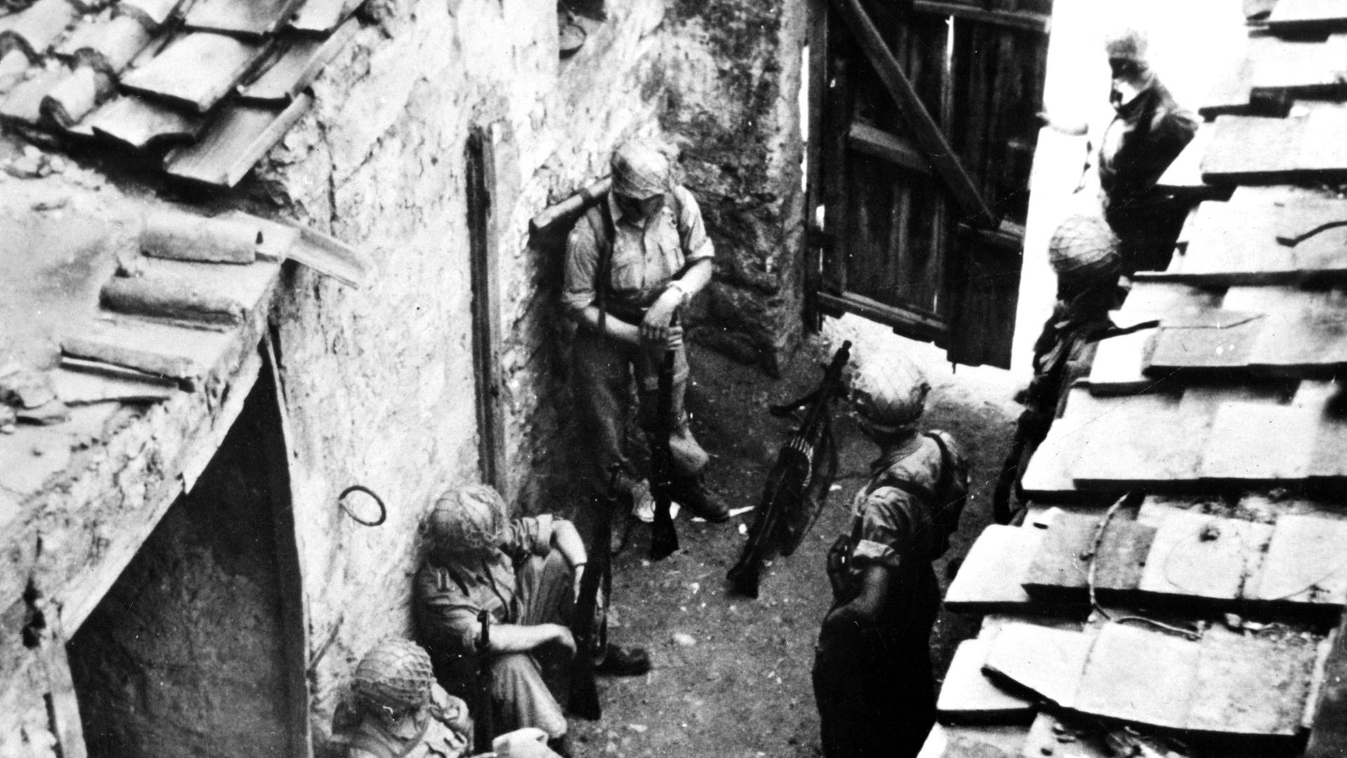 I paracadutisti tedeschi aspettano nel cortile di una casa un ordine di attacco.  Si dice che questa foto sia stata scattata nell'aprile del 1944 nei pressi di un casinò in Italia.