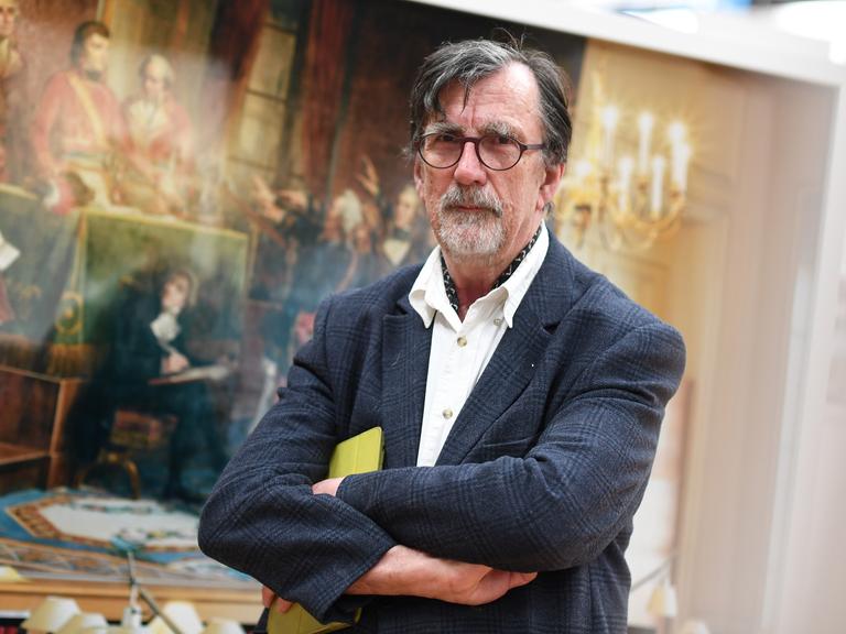 Der Wissenschaftssoziologe und Philosoph Bruno Latour steht vor einem Gemälde und blickt in die Kamera