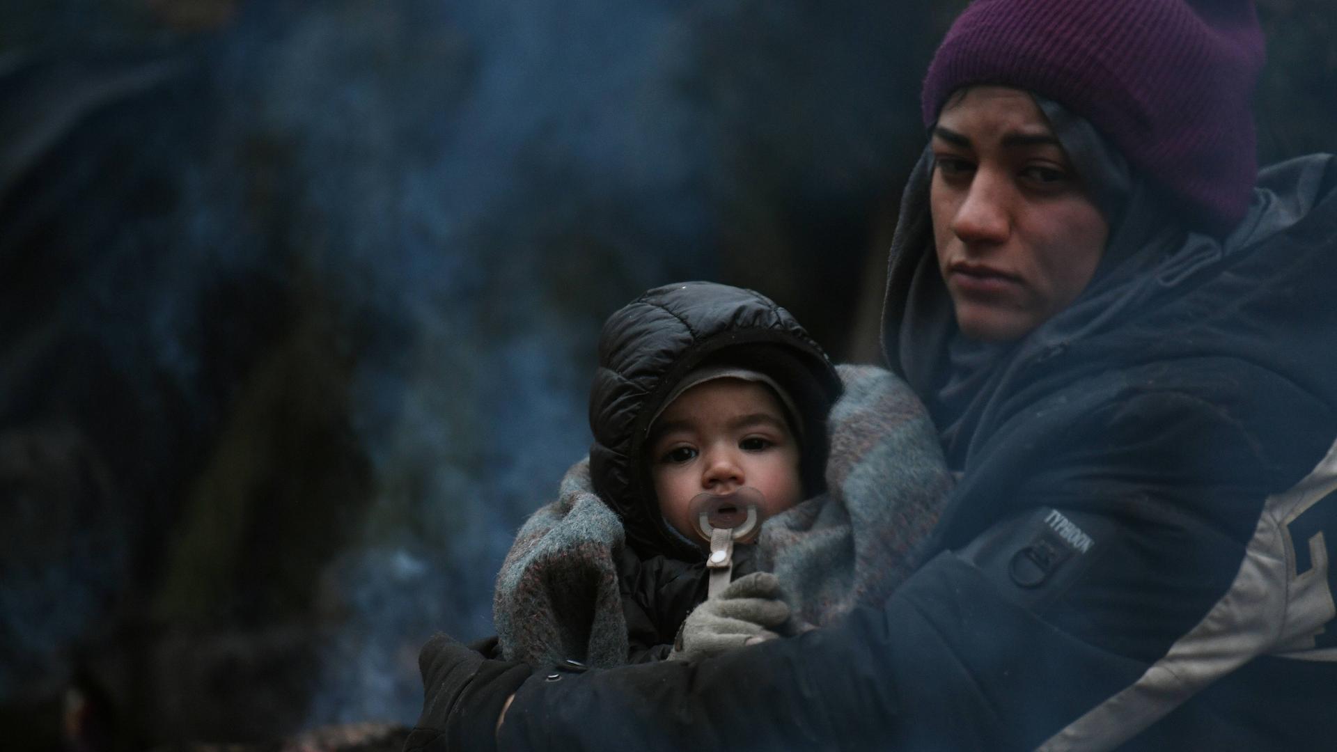 Frau mit Kind wärmt sich am Feuer: Flüchtlinge in Belarus an der Grenze zu Polen.