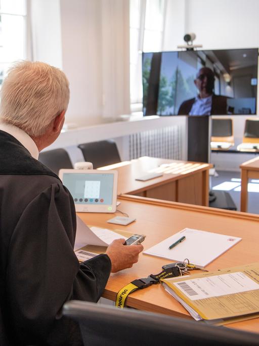 Über einen Monitor per Video zugeschaltet ist ein Rechtsanwalt während einer Verhandlung am Amtsgericht in Frankfurt am Main. Dabei kann der vorsitzende Richter die Kamera am Monitor per Fernbedienung so drehen, dass auch der zugeschaltete Anwalt die Verfahrensbeteiligten sehen kann. 
