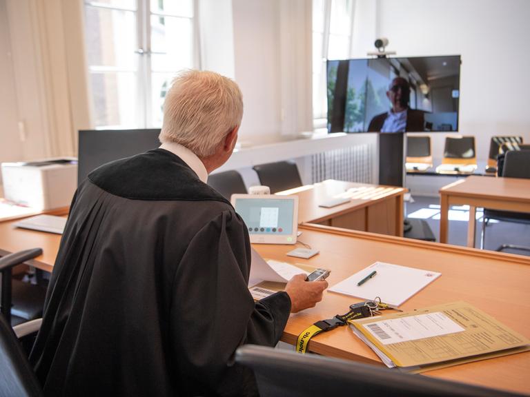 Über einen Monitor per Video zugeschaltet ist ein Rechtsanwalt während einer Verhandlung am Amtsgericht in Frankfurt am Main. Dabei kann der vorsitzende Richter die Kamera am Monitor per Fernbedienung so drehen, dass auch der zugeschaltete Anwalt die Verfahrensbeteiligten sehen kann. 