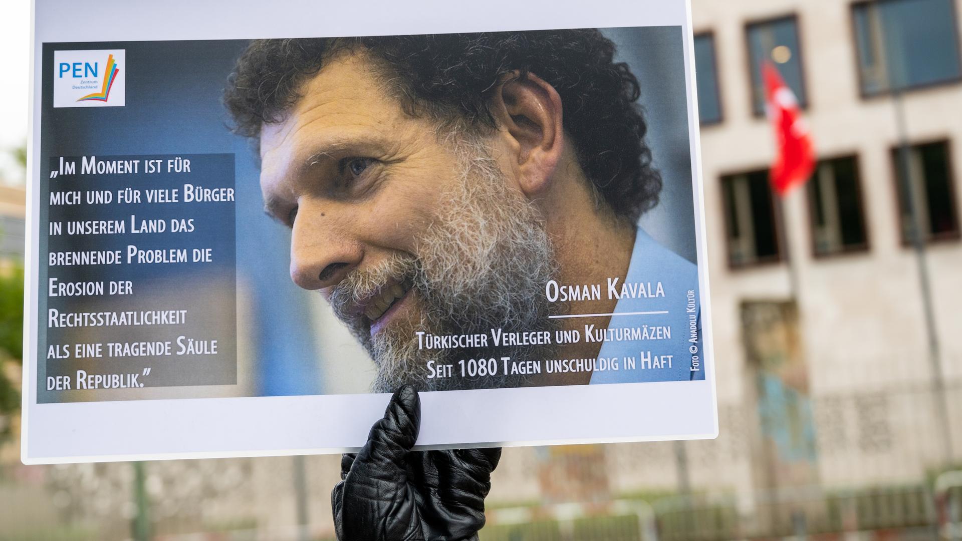 Jemand hält ein Bild von Osman Kavala in die Luft. Jemand hält ein Bild von Osman Kavala in die Luft.