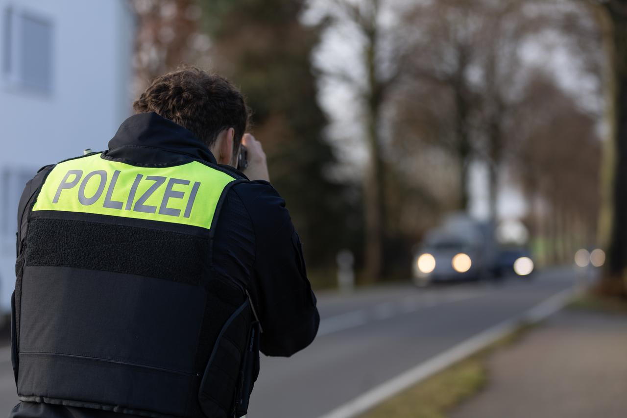 Ein Beamter der Polizei steht mit einem Laser für die Geschwindigkeitsmessung von Fahrzeugen an einer Straße. Ein Beamter der Polizei steht mit einem Laser für die Geschwindigkeitsmessung von Fahrzeugen an einer Straße.