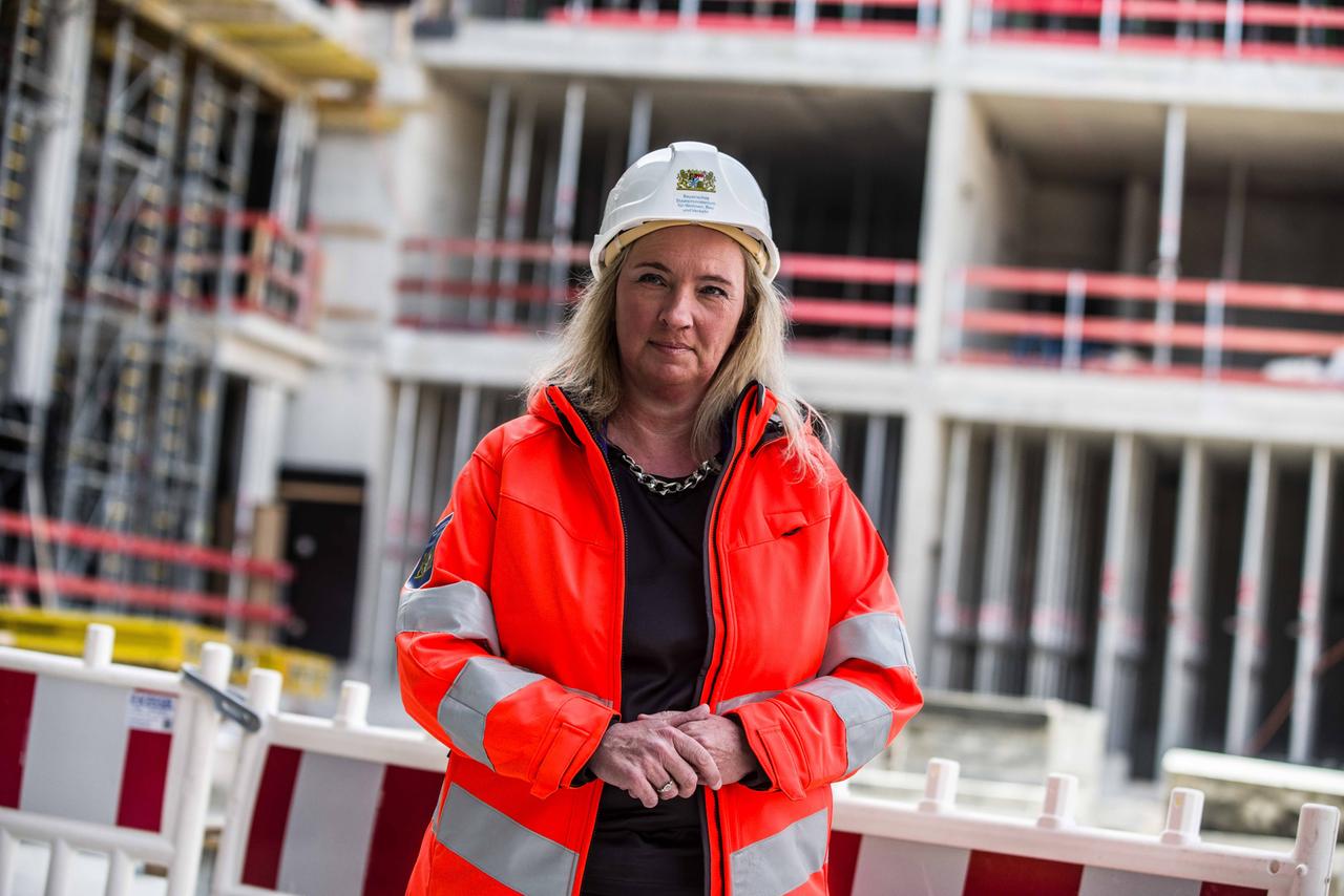 Kerstin Schreyer steht in einer orangefarbenen Warnweste auf einer Baustelle. Kerstin Schreyer steht in einer orangefarbenen Warnweste auf einer Baustelle.