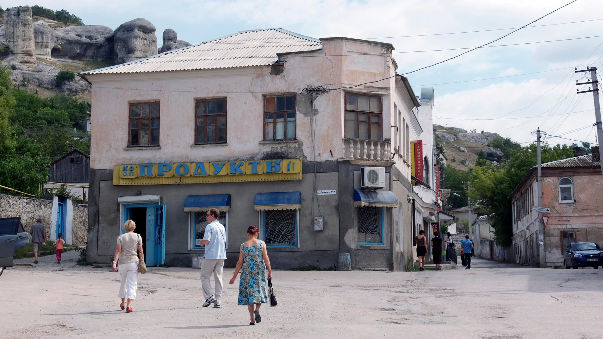 Ein Platz in dem Ort Bachtschyssaraj auf der Halbinsel Krim, die 2014 von Russland annektiert wurde. Das Foto wurde im Spätsommer 2011 aufgenommen. Mehrere Fußgänger überqueren den Platz. Im Hintergrund sind Felsen und Hügel zu sehen.