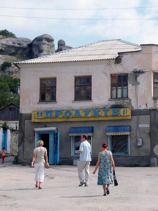 Ein Platz in dem Ort Bachtschyssaraj auf der Halbinsel Krim, die 2014 von Russland annektiert wurde. Das Foto wurde im Spätsommer 2011 aufgenommen. Mehrere Fußgänger überqueren den Platz. Im Hintergrund sind Felsen und Hügel zu sehen.
