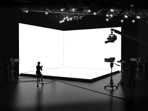 Ein leeres Nachrichtenstudio mit Kameras und weißem Hintergrund.