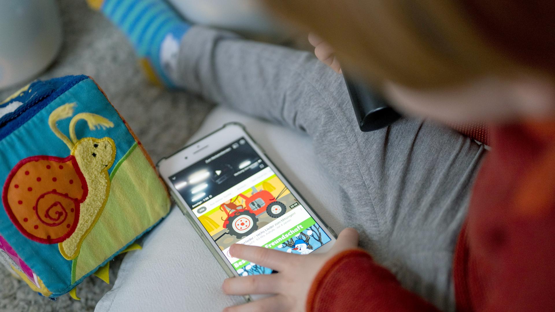 Ein Kleinkind schaut sich Kindervideos auf einem Smartphone an. Ein Kleinkind schaut sich Kindervideos auf einem Smartphone an.