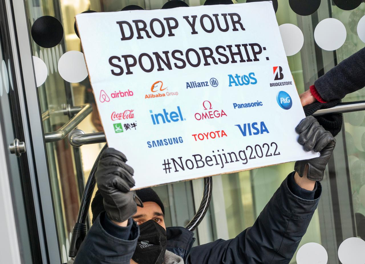 Vor dem Eingang einer Niederlassung der Allianz Versicherung in Berlin steht ein Aktivist mit einem Plakat mit der Aufschrift "Drop your Sponsorship", darunter die Logos von airbnb, Alibaba, Allianz, Atos, Bridgestone, CocaCola, intel, omega, panasonic, P&G, Samsung, Toyota und Visa. Vor dem Eingang einer Niederlassung der Allianz Versicherung in Berlin steht ein Aktivist mit einem Plakat mit der Aufschrift "Drop your Sponsorship", darunter die Logos von airbnb, Alibaba, Allianz, Atos, Bridgestone, CocaCola, intel, omega, panasonic, P&G, Samsung, Toyota und Visa.