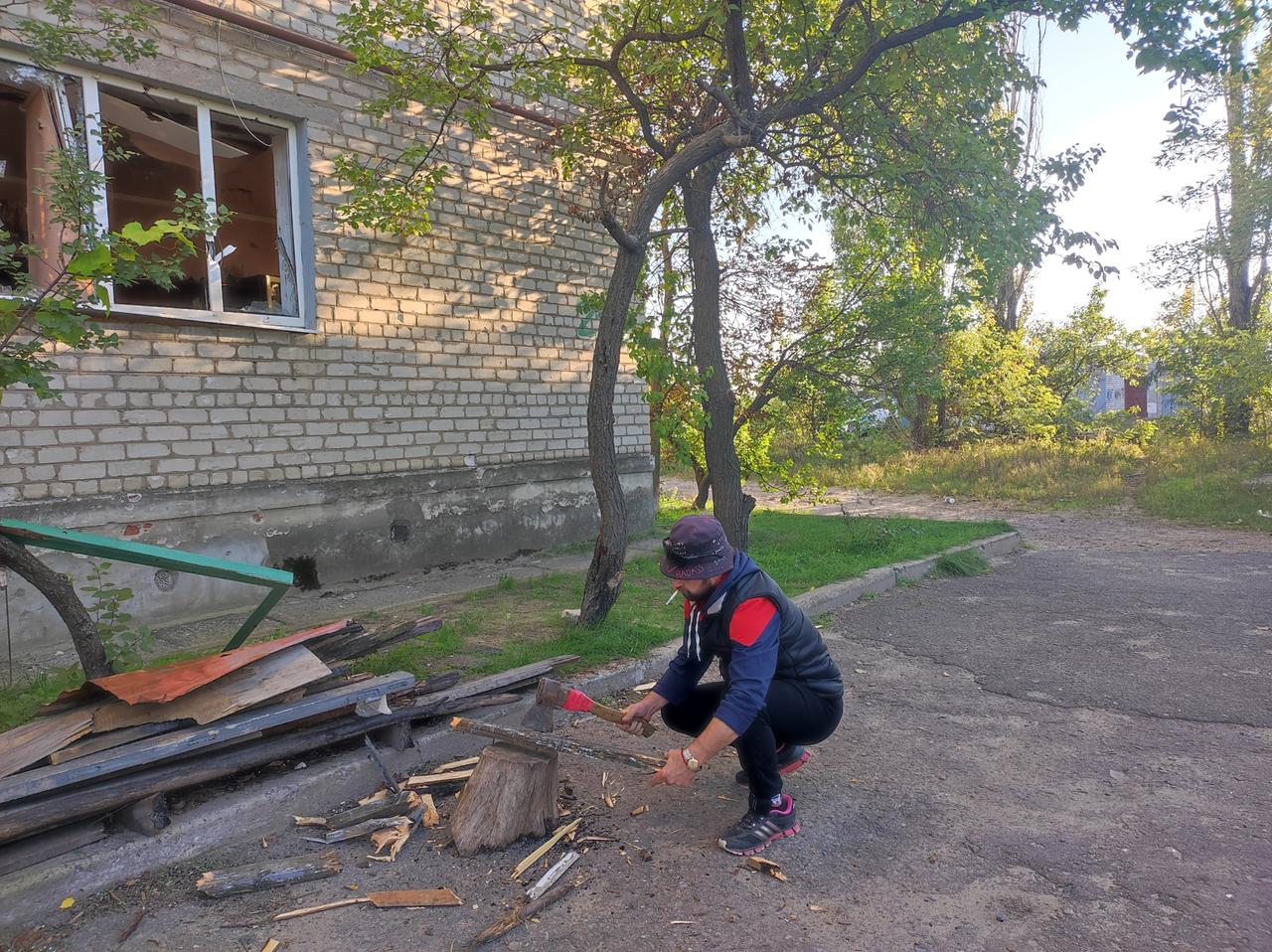 Der Ukrainer Maksim Surschan. Ein Mann hockt vor einem Haus und hackt Holz. Der Ukrainer Maksim Surschan. Ein Mann hockt vor einem Haus und hackt Holz.