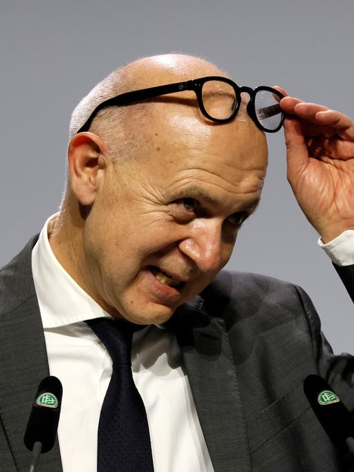 Neuendorf steht auf der Bühne beim DFB-Bundestag und schiebt seine Brille auf die Stirn.